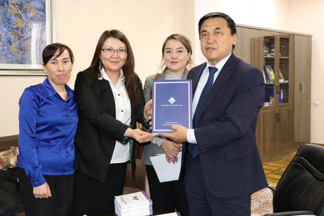 Minister Kanybek Imanaliev (first from right) receiving the books from UCA representatives.